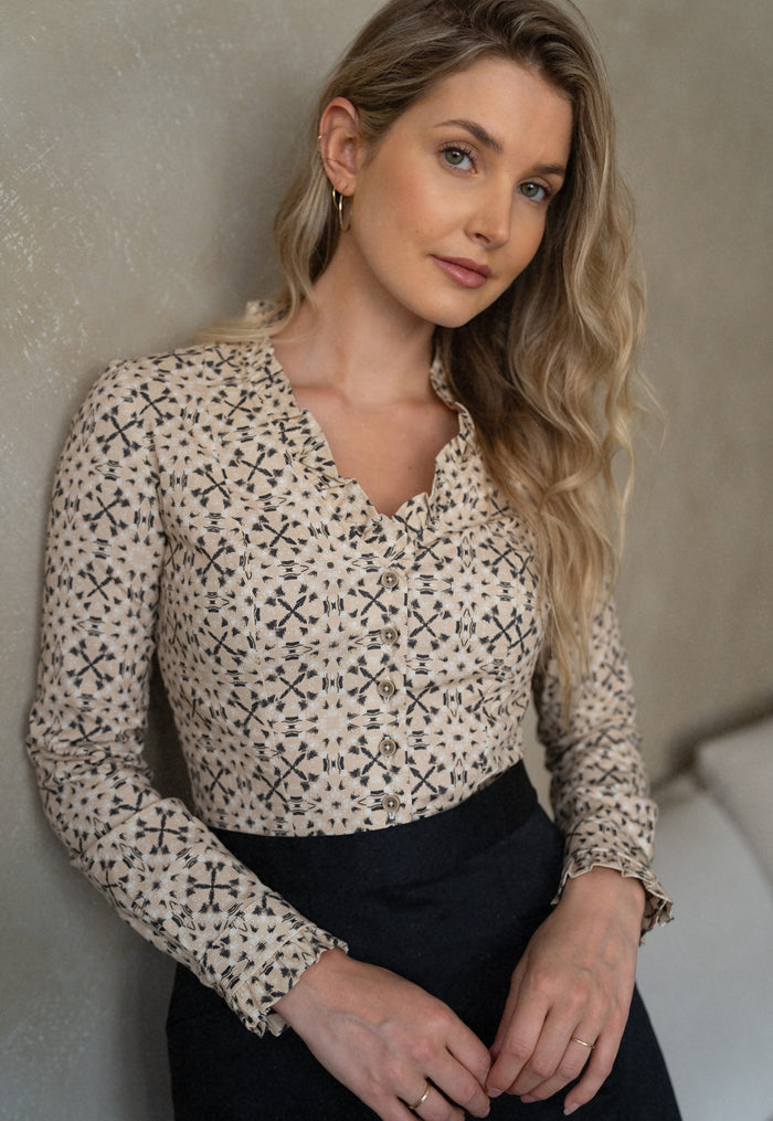 Woman wearing a patterned blouse against a neutral background
